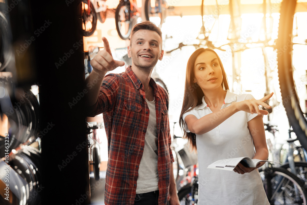 A girl consultant shows the buyer in a bicycle store.