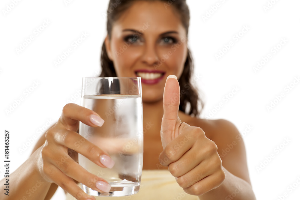 young woman holding a glass of cold mineral water and showing thumbs up young woman holding a glass of cold mineral water and showing thumbs up