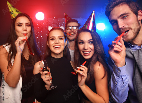 Friends making big party in the night. Five people throwing confetti and drinking champagne.