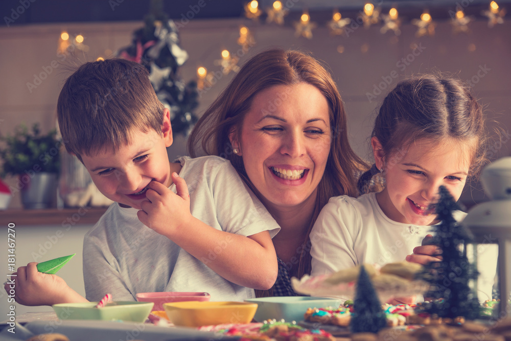 Fototapeta premium Mother with children having fun preparing for Christmas holidays. Joy and happiness