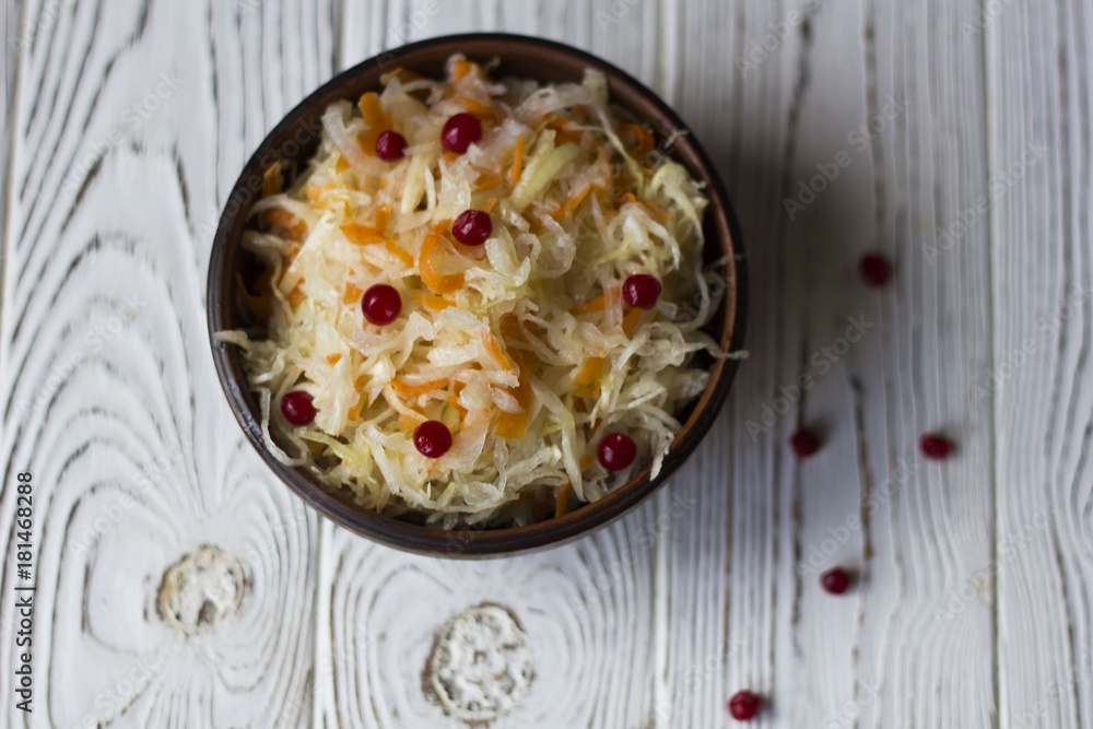 sauerkraut with cranberries in a clay plate on a wooden table