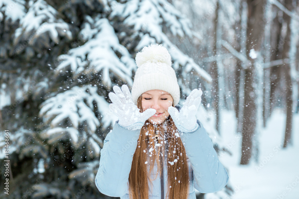 A girl dressed in warm winter clothes and a hat posing in a winter forest. Model with a beautiful smile near the Christmas tree. A girl dressed in warm winter clothes and a hat posing in a winter forest. Model with a beautiful smile near the Christmas tree.
