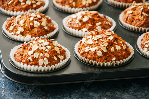 Carrot cake muffins with nuts, raisins and oats on a blue stone background.