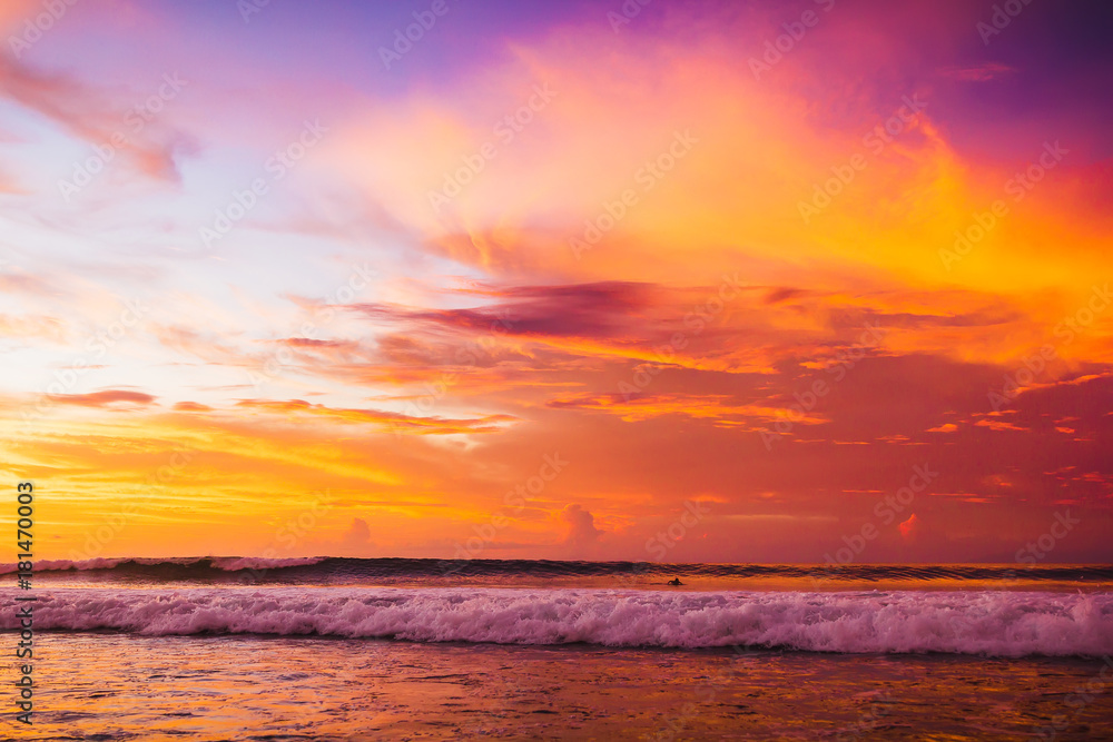 Ocean with waves at colorful bright sunset with clouds