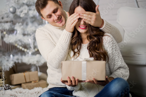 Senior couple in front of Christmas tree with presents.