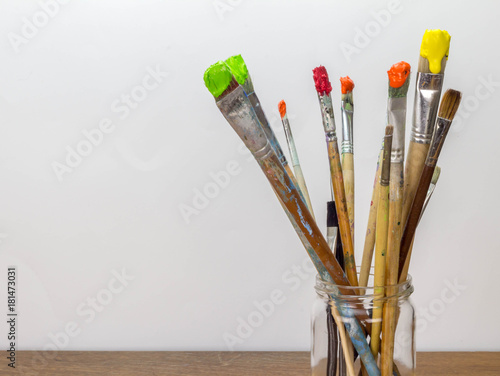 Photo of dirty paint brushes in glass jar on wooden table