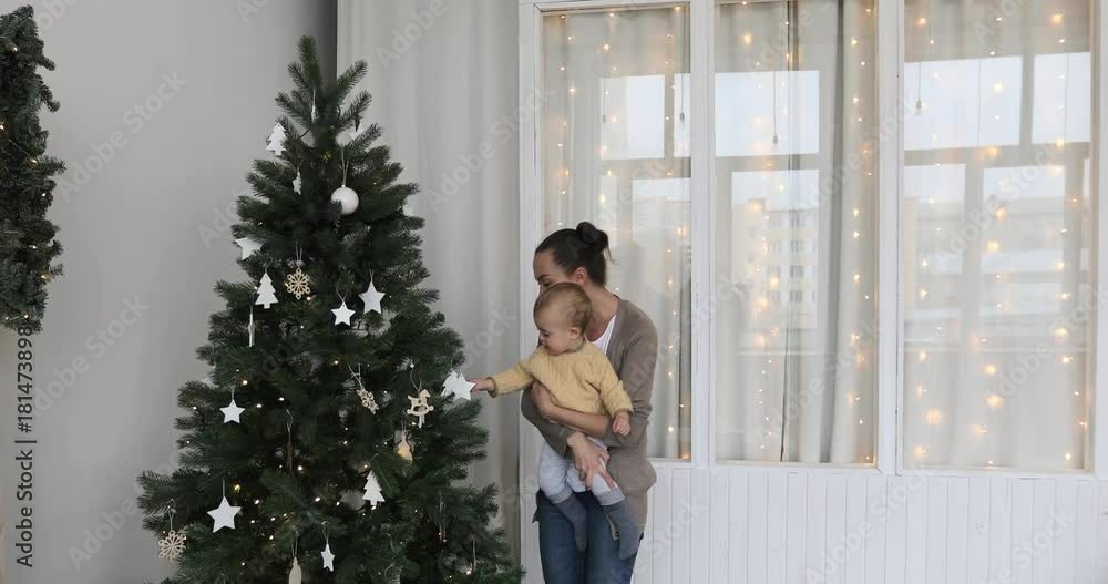 Christmas concept. Little baby boy with mother in sweater decorates the Christmas tree. Year-old child waiting New Year , happy family concept Christmas concept. Little baby boy with mother in sweater decorates the Christmas tree. Year-old child waiting New Year , happy family concept