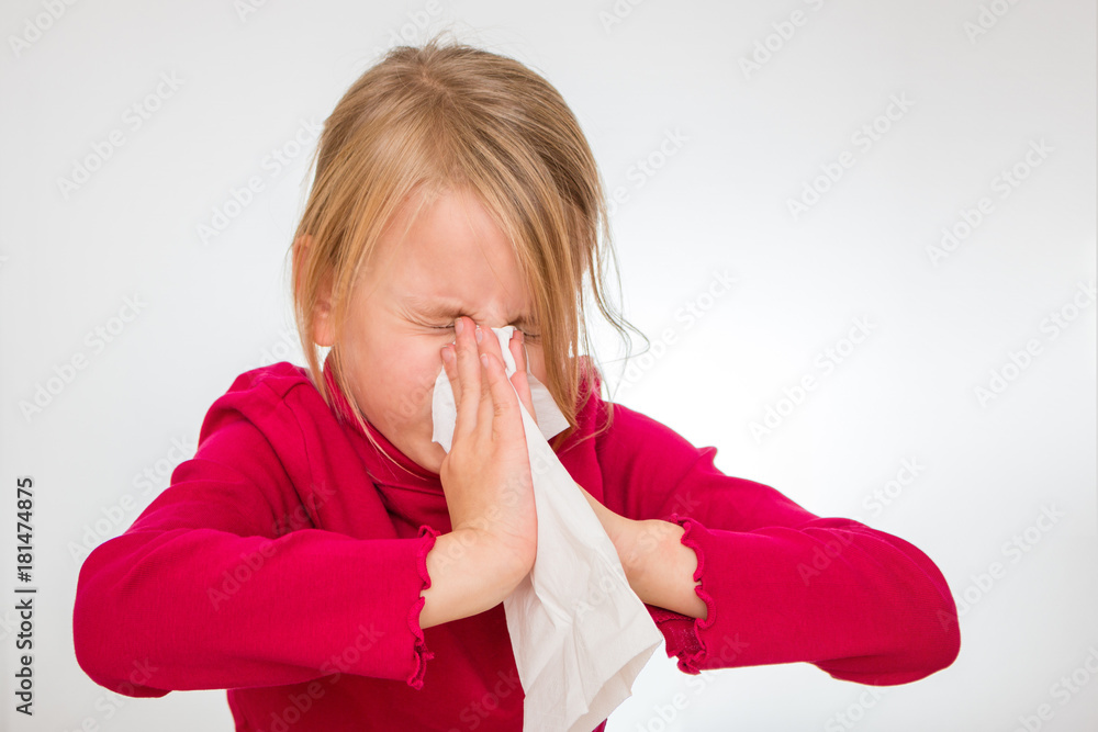 Ein Mädchen schnäuzt in ein weißes Taschentuch. Sie ist 7 Jahre alt und  trägt einen roten Pullover. Freisteller Stock Photo | Adobe Stock