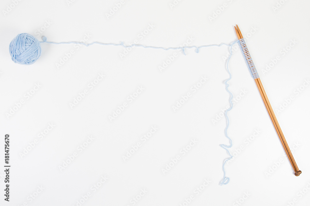 Knitting needles and blue yarn ball on white background as frame with copy space for text Knitting needles and blue yarn ball on white background as frame with copy space for text