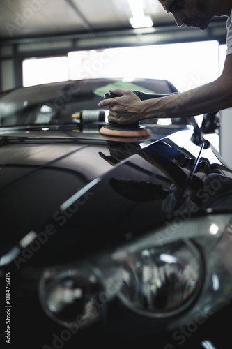 Car detailing - Hands with orbital polisher in auto repair shop. Selective focus.