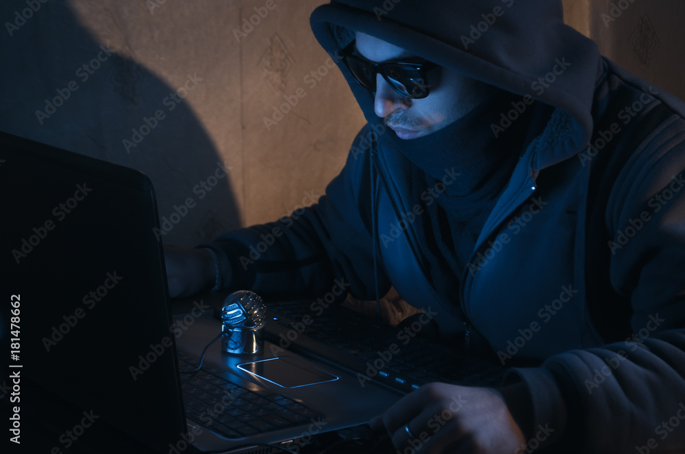 hacker in a hood in a dark room, the intruder breaks into a system
