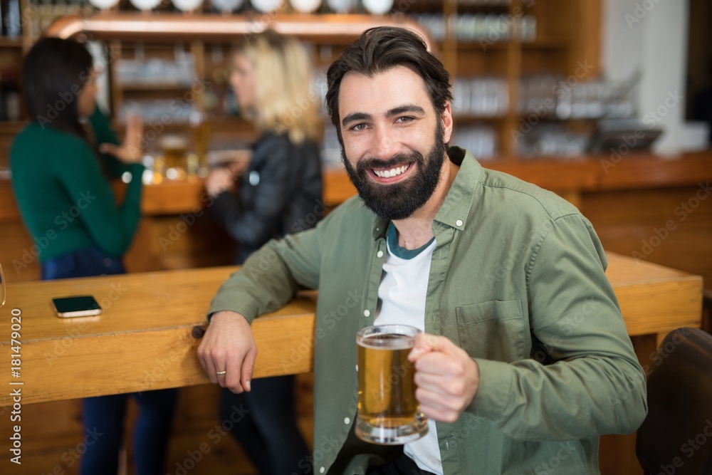 Happy man holding glass of beer in bar