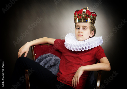 Crowned boy sitting in an armchair photo