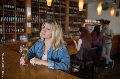 Thoughtful woman having glass of wine at counter