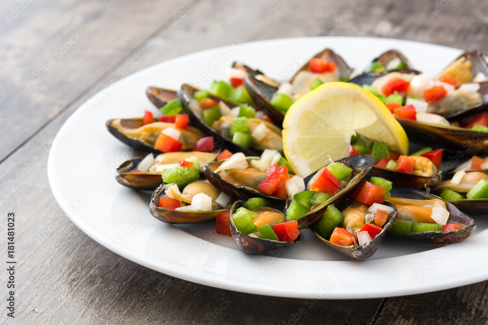 Steamed mussels with peppers and onion on wooden table