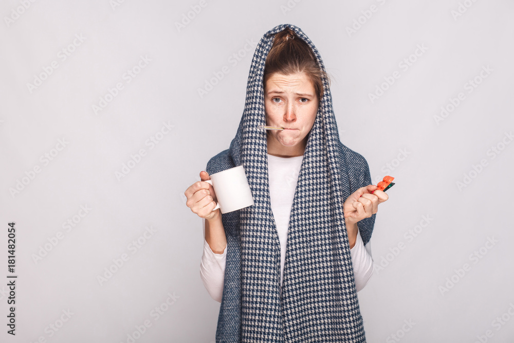 Young woman with gray scarf, holding cup, thermometer and pills - obrazy, fototapety, plakaty 