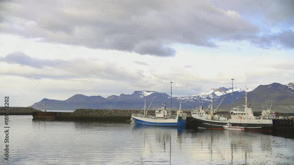 Northern harbor port with fishing and whale watching boats and little ships and snow mountains with moving clouds at sunset Northern harbor port with fishing and whale watching boats and little ships and snow mountains with moving clouds at sunset