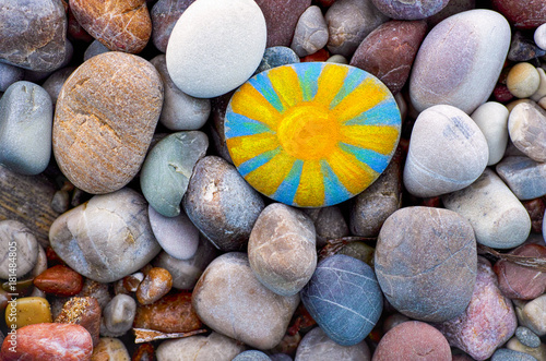 Bright sun painted on pebble. photo