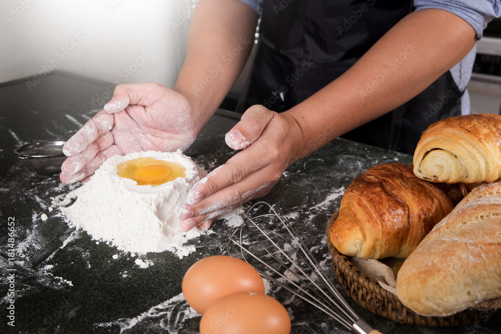 Fototapeta Woman's hands knead dough with flour, eggs and ingredients. at kitchen.