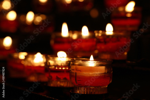Red candles burning in dark church close up