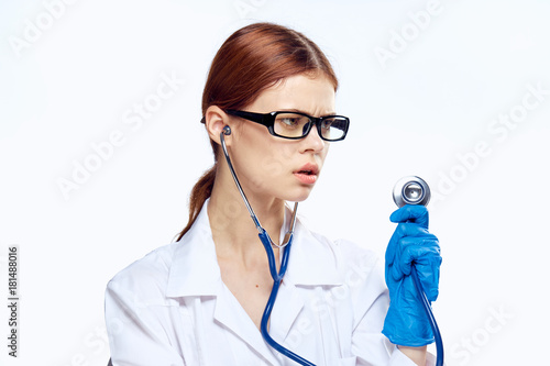 Beautiful young woman in glasses and in medical dressing gown holds a stethoscope on white isolated background, doctor, medicine