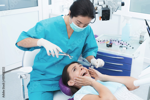 A female dentist is treating a patient. She sits on the dental chair and is afraid.