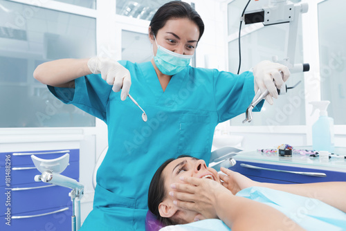 A female dentist is treating a patient. She sits on the dental chair and is afraid.