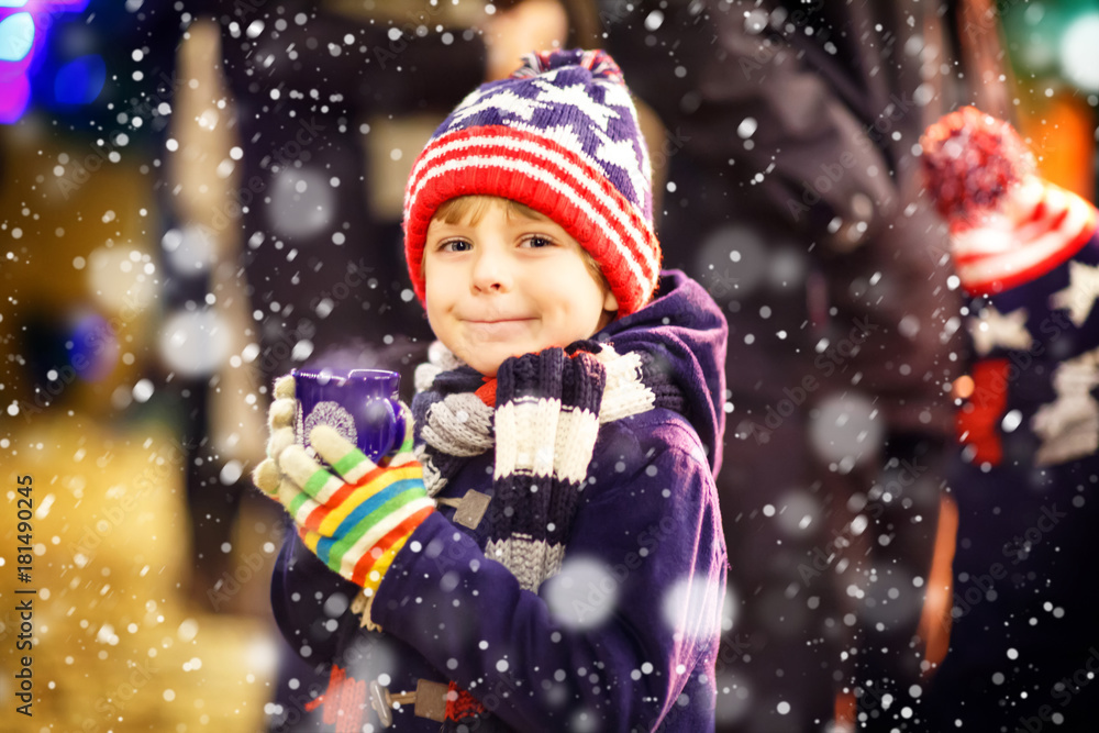 Little kid boy drinking hot chocolate on Christmas market