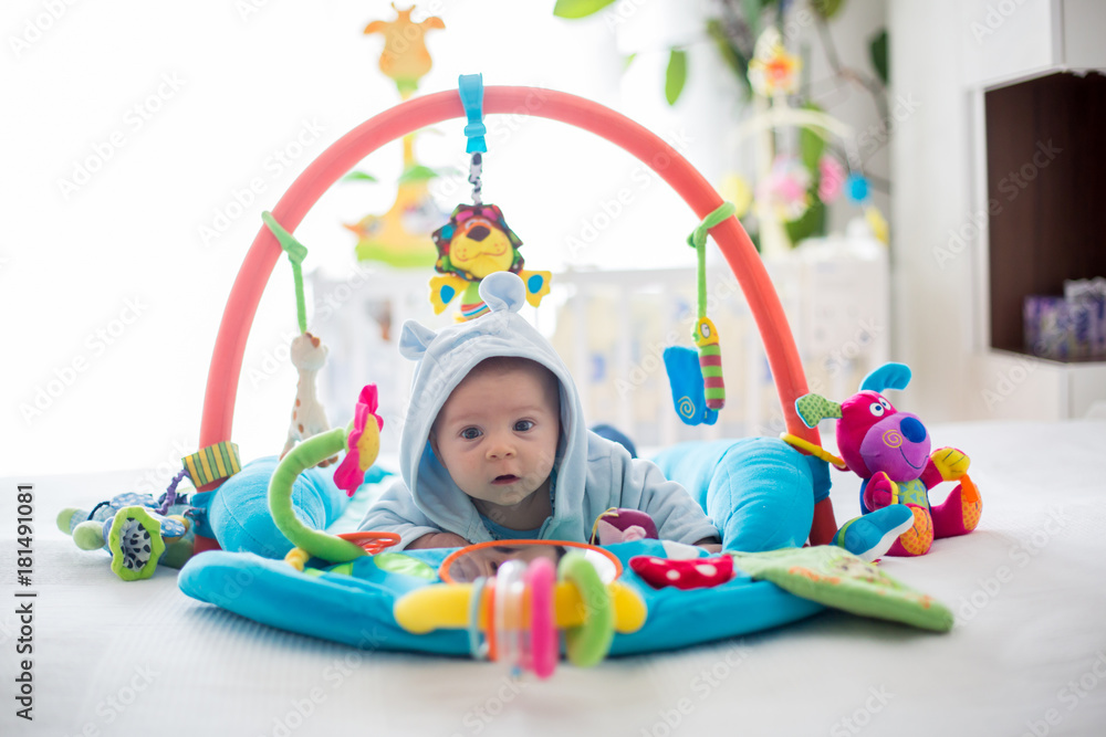 Cute baby boy on colorful gym, playing with hanging toys at home Cute baby boy on colorful gym, playing with hanging toys at home
