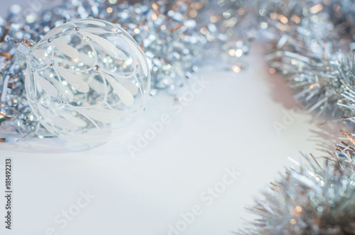 White glass decoration ball on a white background with silver tinsel around