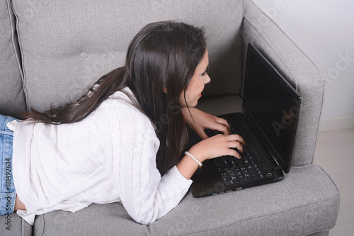 Woman using laptop on couch.