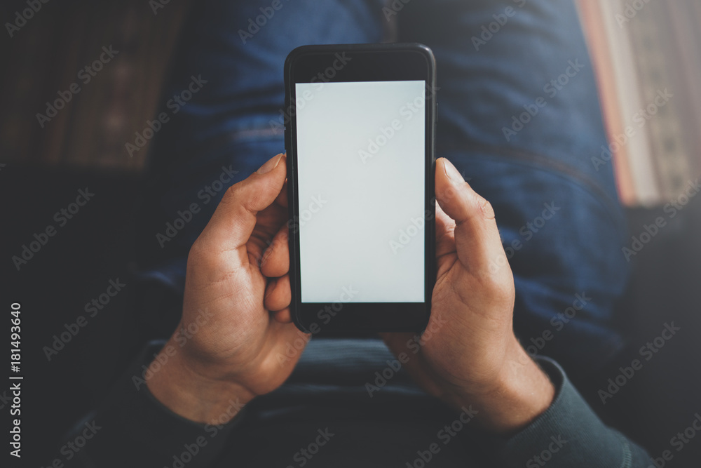 Close-up view of male hand holding modern smartphone with blank white screen. Blurred background.Blogger using mobile gadget. Horizontal mockup. Close-up view of male hand holding modern smartphone with blank white screen. Blurred background.Blogger using mobile gadget. Horizontal mockup.