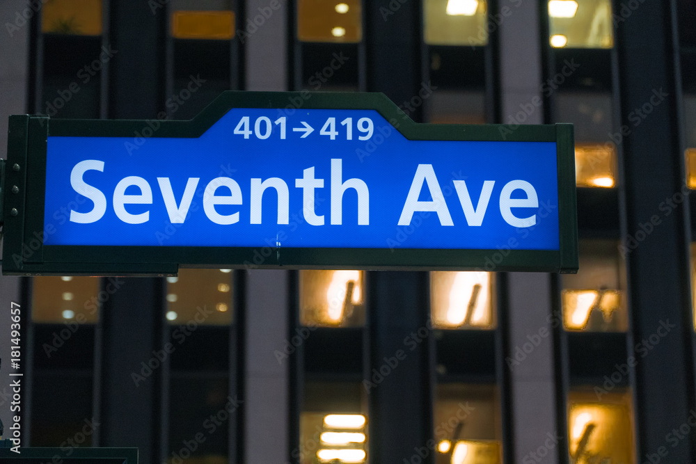 Obraz premium Seventh Avenue lit up sign at night in Manhattan New York City. Directional street sign for drivers to navigate through roads in midtown