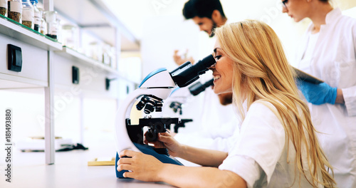 Group of scientists doing research looking through microscope