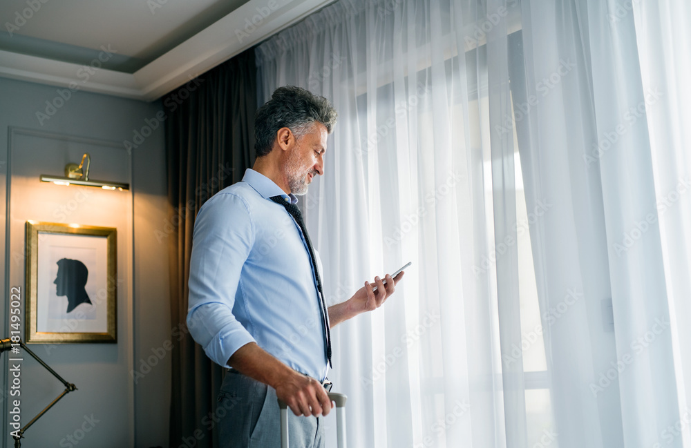 Mature businessman with smartphone in a hotel room. Mature businessman with smartphone in a hotel room.