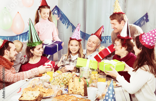 Large family handing gifts to birthday girl