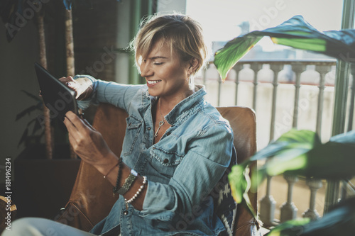 Εκτύπωση καμβά Smiling young woman wearing casual clothes and using electronic device while spending relax time home livingroom