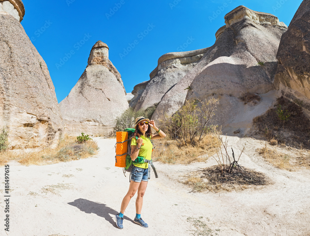Young happy woman traveler alone hiking with backpack in the Pasabag valley of Cappadocia, Turkey