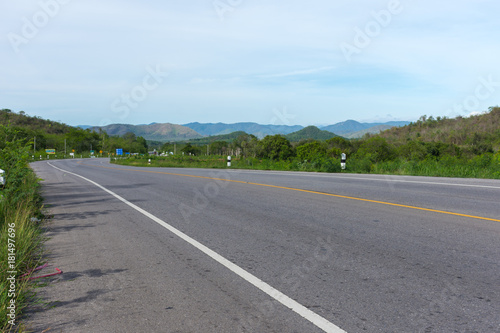 Stretched road along with trees and scenic view of mountain and blue sky