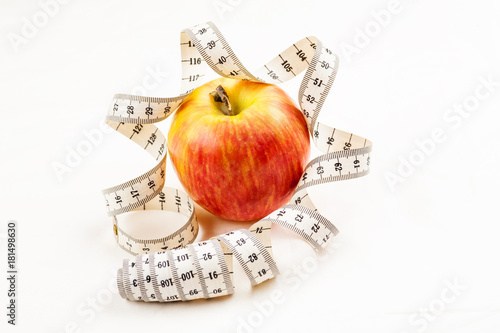 Ripe red juicy apple with measuring tape around it on a white background photo