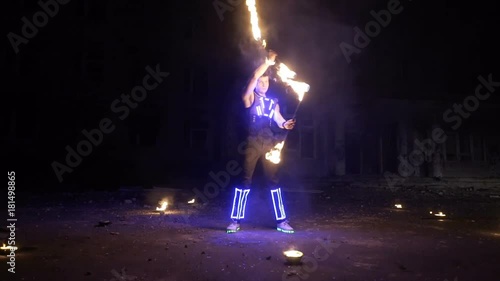 Fire show performance. Handsome male fire performer twirling and tossing up fire baton staff ignited from both sides. photo