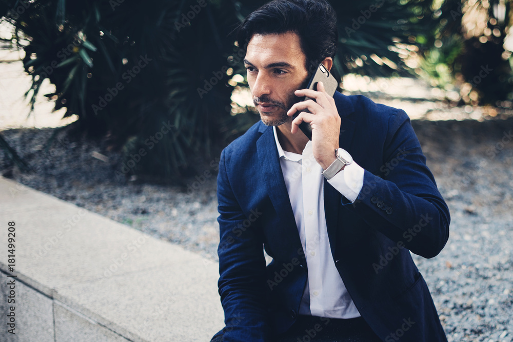 Elegant young businessman working outside with mobile laptop pro. Handsome man using modern smartphone for call.Blurred background.Horizontal.Cropped. Elegant young businessman working outside with mobile laptop pro. Handsome man using modern smartphone for call.Blurred background.Horizontal.Cropped.
