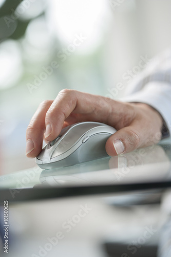 male hand clicking a cordless computer mouse on a green table