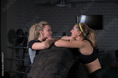 Fototapeta Naklejka Na Ścianę i Meble -  Fitness women are posing near a tire in the gym.
