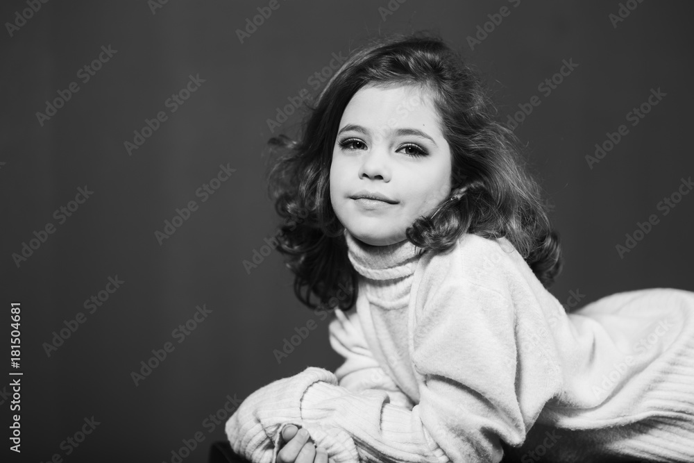 Little beautiful girl with brown hair in a light sweater and a skirt of tulle. Studio. A princess poses for a photographer.