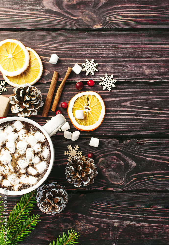 A cup of hot coffee with marshmallow, spruce branches, cones, Christmas gifts, mugs of orange, snowflakes, cinnamon. Traditional festive decoration Christmas dark background top view. A cup of hot coffee with marshmallow, spruce branches, cones, Christmas gifts, mugs of orange, snowflakes, cinnamon. Traditional festive decoration Christmas dark background top view.
