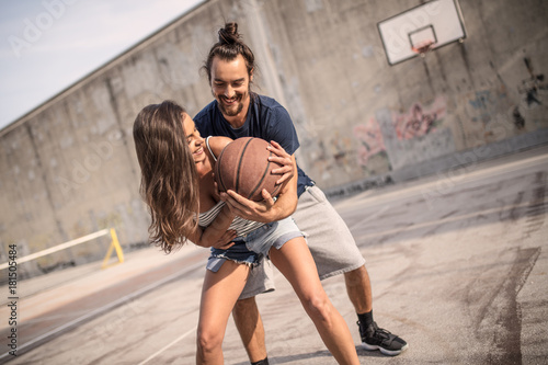 beautiful couple hanging out  flirting and relaxing while playing games on an asphalt basketball court