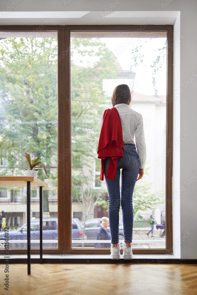 Vertical rearview shot of a stylish woman standing near the window looking out lifestyle recreation coziness home future youth planning concept. Vertical rearview shot of a stylish woman standing near the window looking out lifestyle recreation coziness home future youth planning concept.