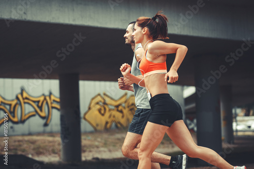 Fototapeta Naklejka Na Ścianę i Meble -  Couple of runners jogging on the city street .City environment.