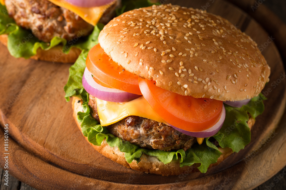 Close-up photo of home made hamburger with beer made of beef, onion, tomato, lettuce, cheese and spices. Fresh burger closeup on wooden rustic table with potato fries and chips. Close-up photo of home made hamburger with beer made of beef, onion, tomato, lettuce, cheese and spices. Fresh burger closeup on wooden rustic table with potato fries and chips.